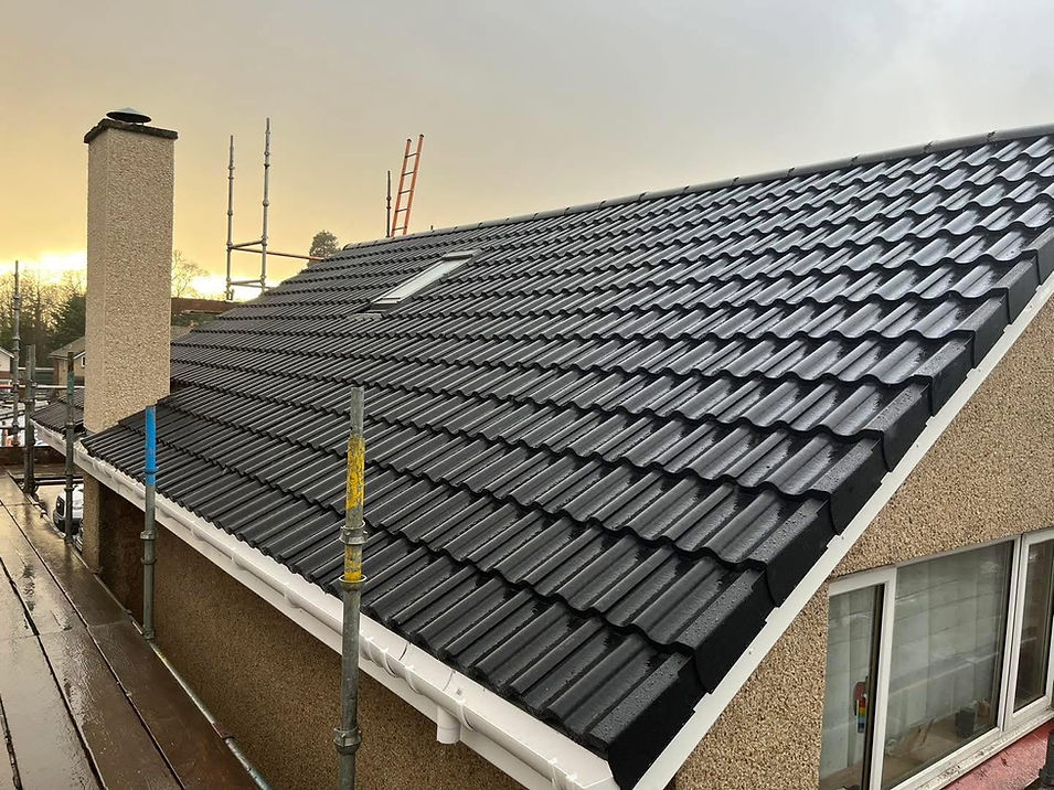 Newly tiled dark grey roof with skylight and stone chimney on a residential home