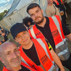 Security team members wearing high-visibility festival vests taking a selfie