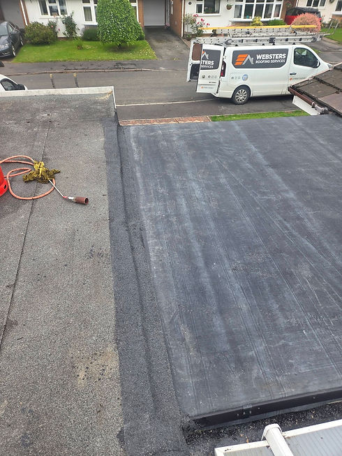 Flat roof under construction with work equipment and a company van parked nearby