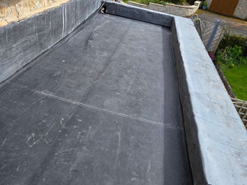 Newly felted flat roof section showing raised edges and lead flashing