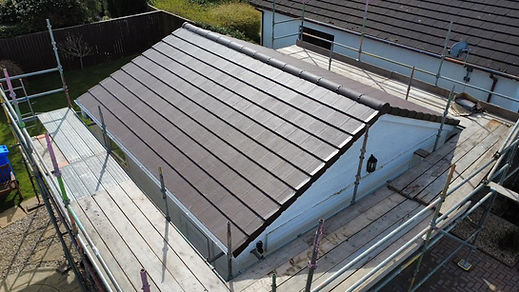 High-angle view of a newly installed tiled roof section with scaffolding along the perimeter