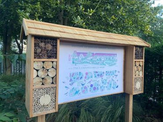 Timber message board flanked by two integrated multi-tier bug hotels