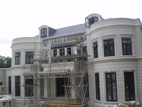 Grand white residential house under renovation with scaffolding around the front