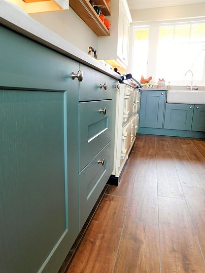 Teal blue fitted kitchen cabinets with wooden countertops and a ceramic sink