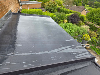 Wide view of a completed black felt flat roof over a residential property