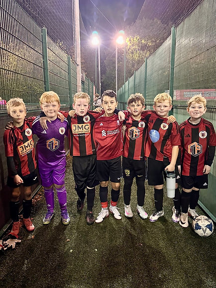 Young football team standing together in matching red and black sports kits