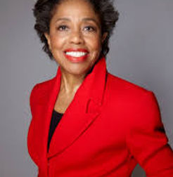 woman in orange jacket and black shirt facing the camera