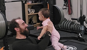 Coach Stephen smiling and holding his young daughter, symbolizing strength and mobility for an active family life.