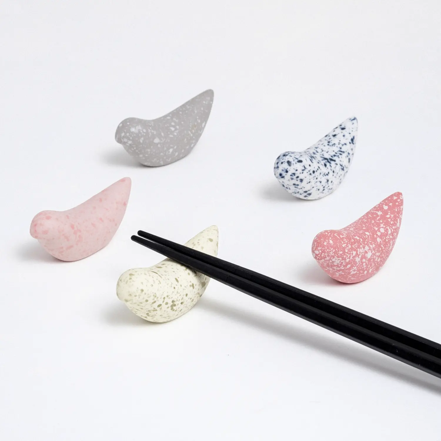 Five blue bird-shaped ceramic chopstick rests, each a different colour specked glaze (grey, white, red, yellow, pink)