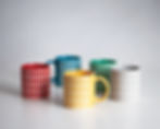 Five colorful mugs with grid patterns against a white background. Designed by Angle in Japan, each mug's grid pattern is created by textured glaze. Colours from left to right: red, blue, yellow, green, grey