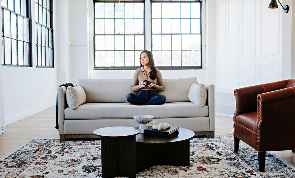 Woman sitting on Gramercy condo sofa cross-legged with a mug in hand