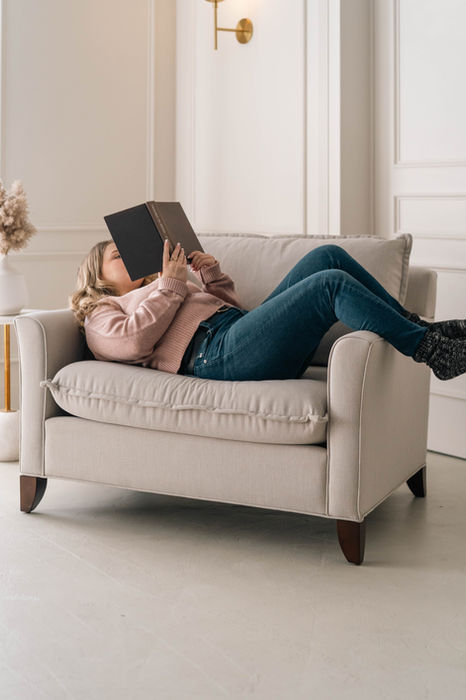 Woman laying in Genevieve chair-and-a-half from Vogel and reading a book