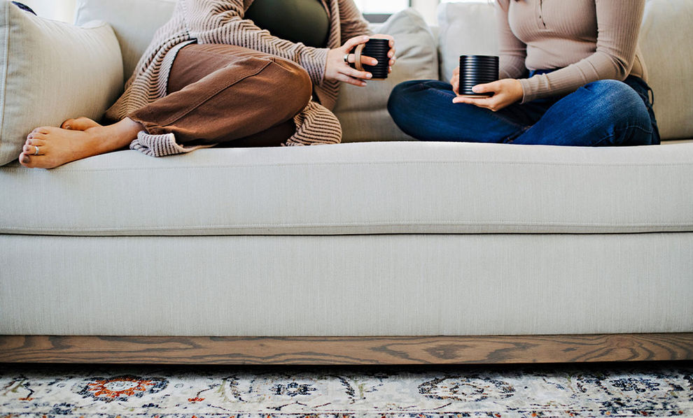 Two women sitting on Gramercy modern condo sofa with bench seat