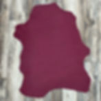 Berry red Italian lambskin leather hide on a wood background