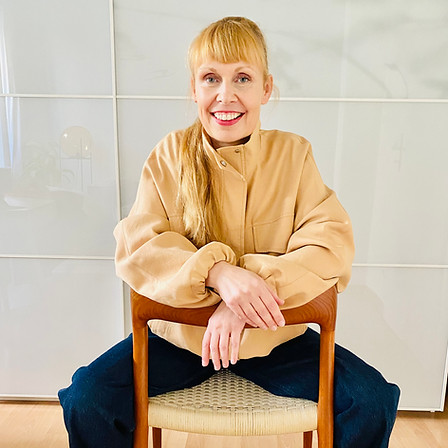 Andrea Schröder, lachend auf einem Stuhl sitzend