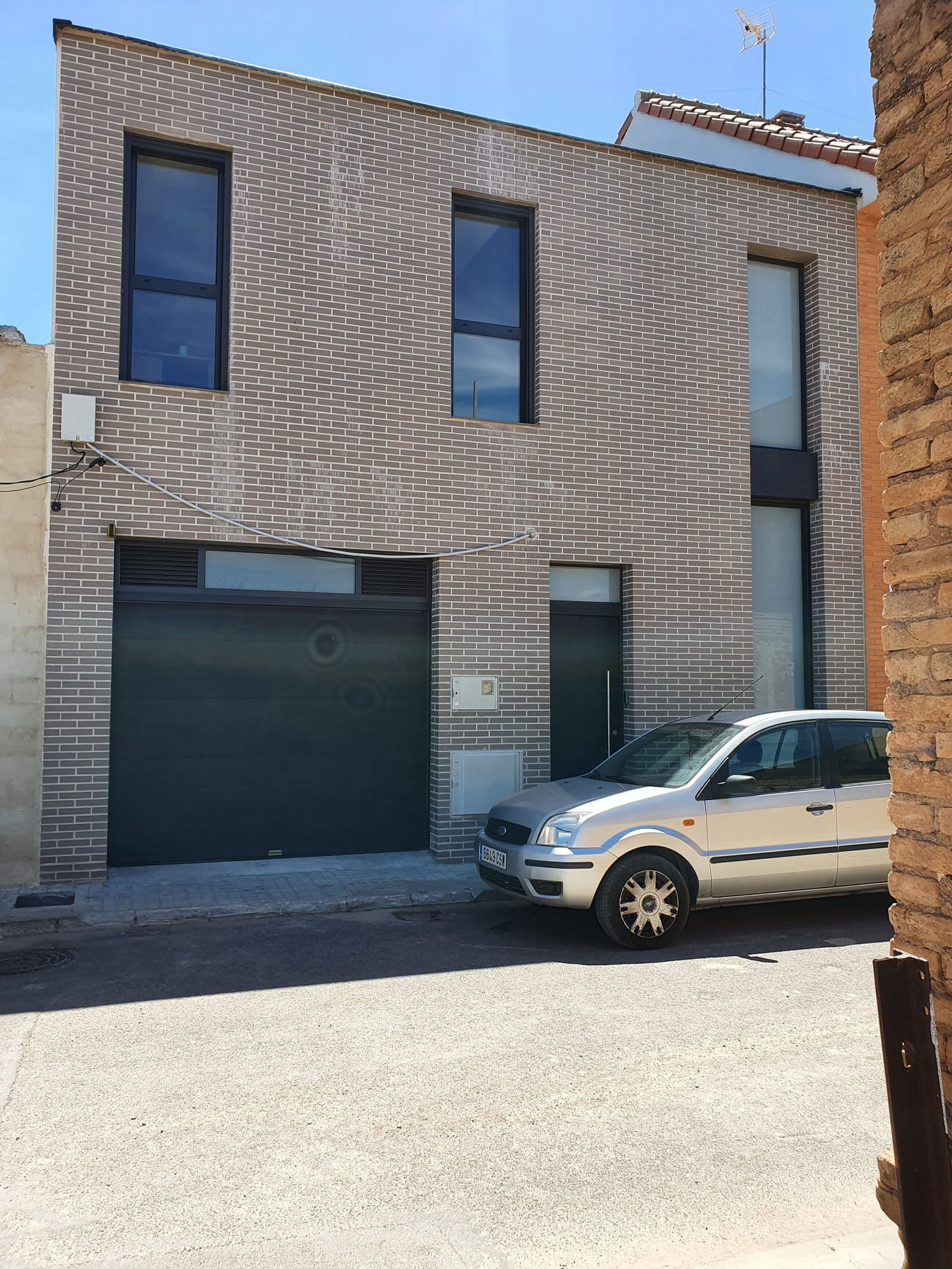 Fachada contemporánea con ladrillo visto y garaje integrado en vivienda unifamiliar Casa Chiva diseñada por Genovés Calleja Arquitectos.