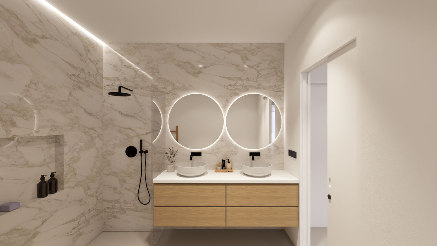 Baño principal moderno con doble lavabo sobre mueble de madera, espejos redondos retroiluminados y ducha con revestimiento efecto mármol en vivienda unifamiliar Passivhaus de Genovés Calleja Arquitectos.