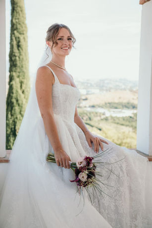 Novia en Hacienda San José en Mijas con ramo de flores y vistas al paisaje de Málaga