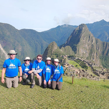 Guided tour group at Machu Picchu viewpoint with Huayna Picchu mountain