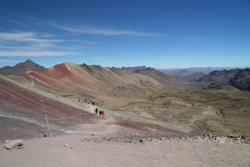 Hikers celebrating at the colorful slopes of Rainbow Mountain and Red Valley in the Peruvian Andes near Cusco