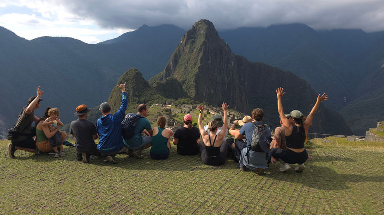 Group of travelers celebrating at Machu Picchu with Huayna Picchu mountain