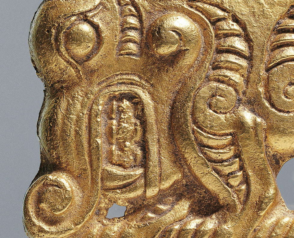 寧夏固原博物館:春秋戰國動物紋金飾牌 Close-up of intricately carved golden ornament with swirling patterns and textured surface, showcasing detailed craftsmanship on a gray background.