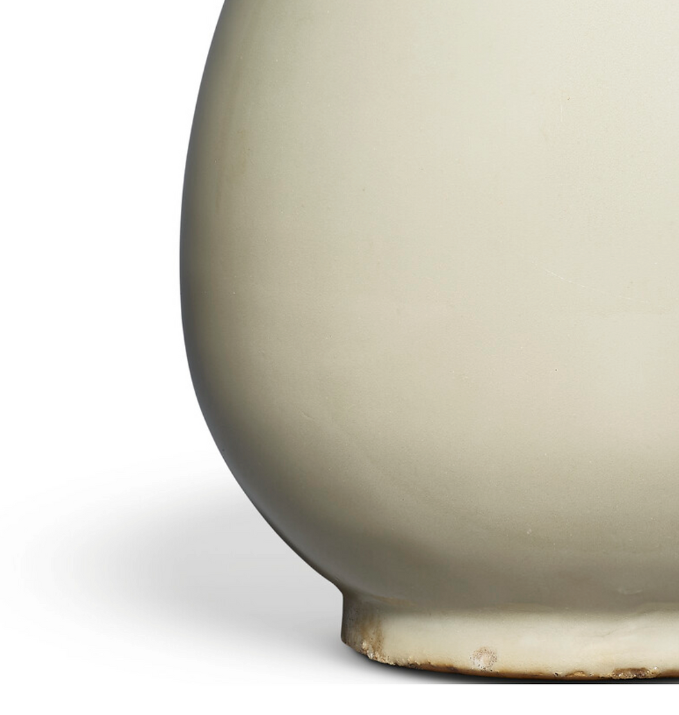 Close-up of a cream-colored, rounded ceramic vase on a white background. The surface is smooth, with slight imperfections and earthy tones.