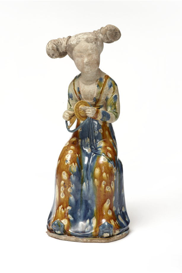唐三彩藍釉坐姿女俑，持鈸，正面，亞洲協會 1979.113 Ceramic figure of a seated woman, wearing a colorful blue and orange robe, with double buns hairstyle. She's holding a ring, calm expression.