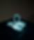 Turquoise ceramic four-cup candle holder with loop handle on a dark background, softly lit and centered.