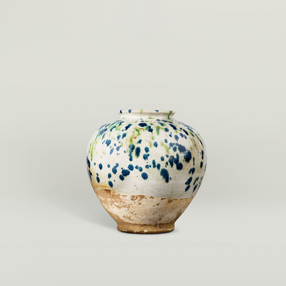 Ceramic vase with blue and green speckles on a light background. Earthy base. Simple setting. Rustic and artistic mood.