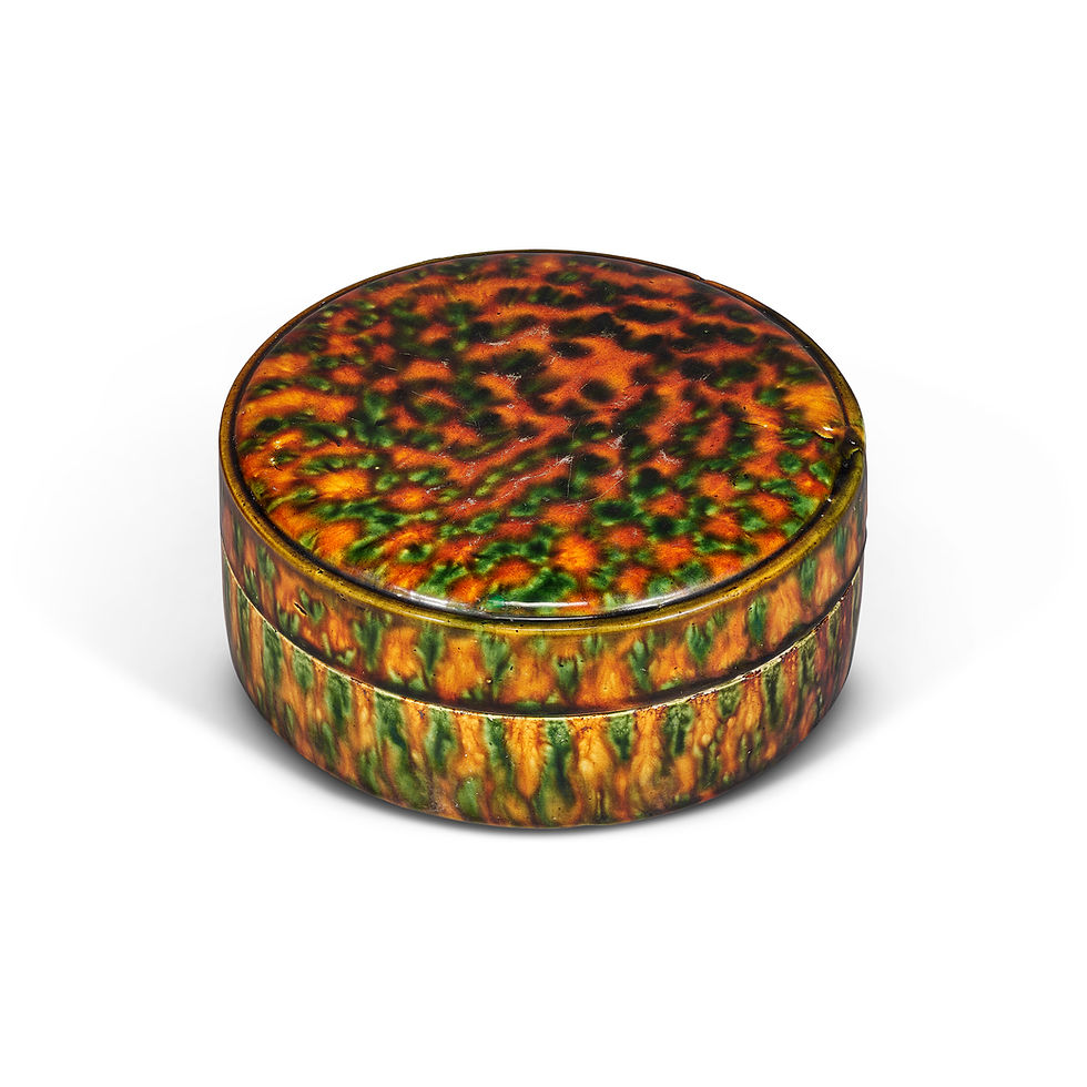Round ceramic box with a green, orange, and brown speckled pattern, set against a plain white background.