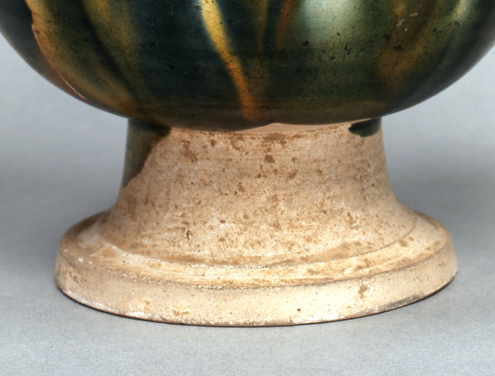 広田松繁,三彩藍釉水注 Ceramic base of a vessel with mottled green and brown glaze on top, rough beige surface below, set against a neutral background.
