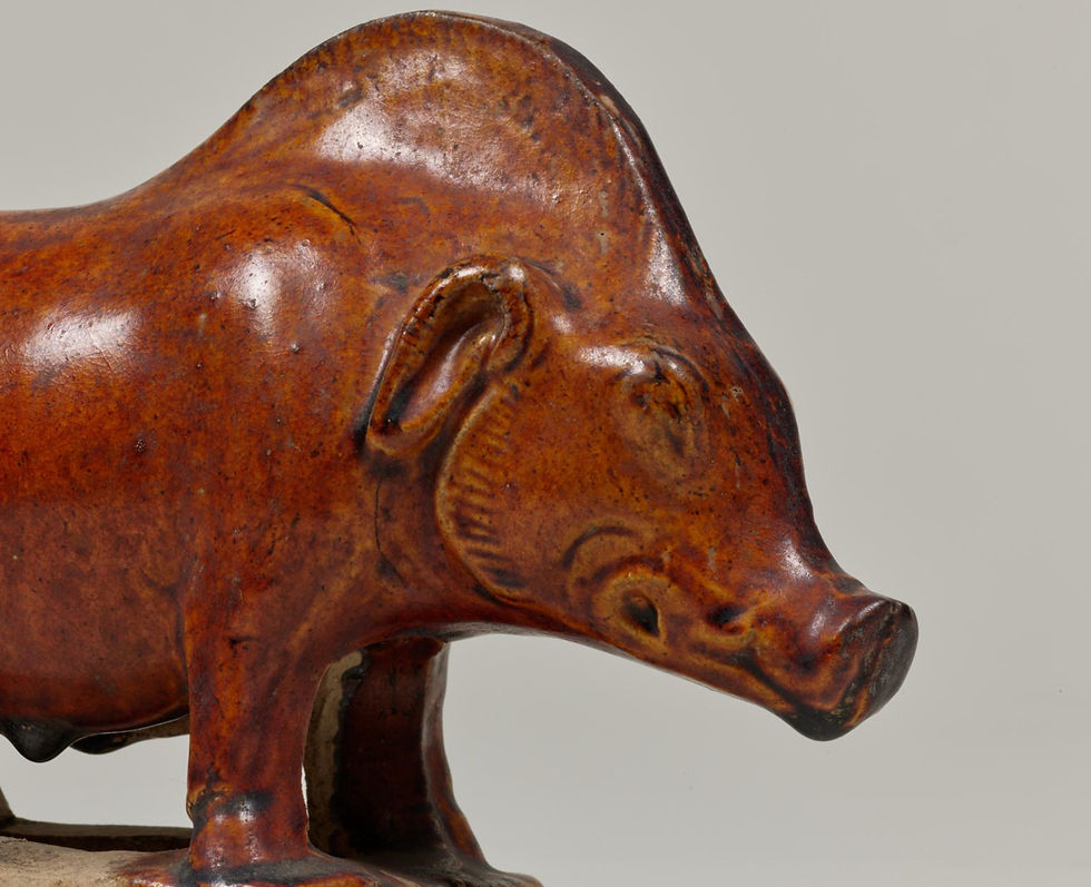 東京國立博物館:唐三彩褐釉豬 A shiny, brown ceramic sculpture of a boar on a plain background. The texture is smooth and the boar's expression is calm.
