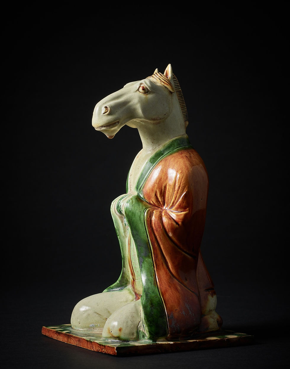 Ceramic sculpture of a horse-headed figure kneeling on a dark background, wearing a robe with green and brown tones.