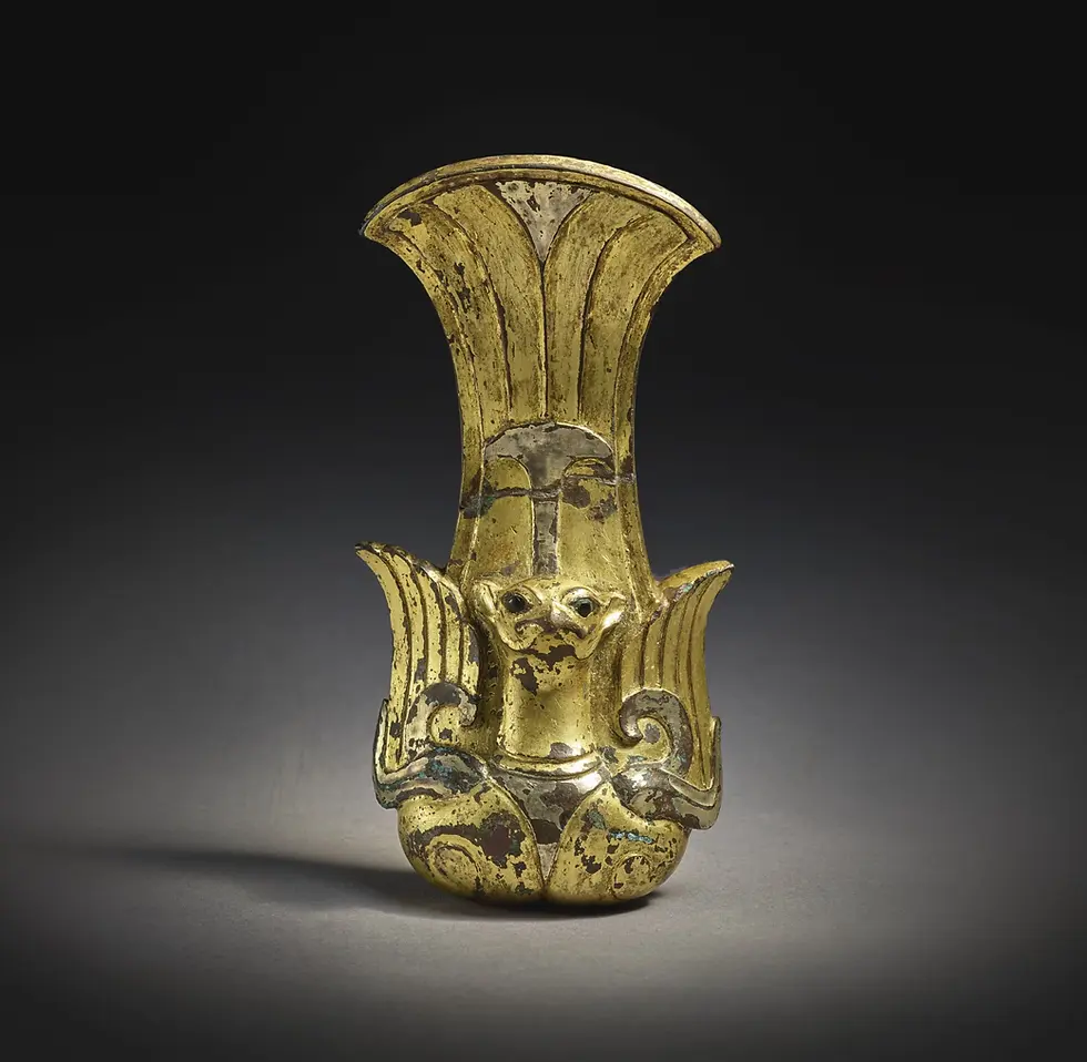 Ancient gold figurine or vessel with a flared top and small face, worn and tarnished, isolated on a dark background.