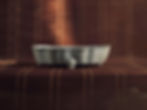 Ceramic bowl with crackled pattern on a brown woven mat background, lit from above. The setting is calm and muted in tone.
