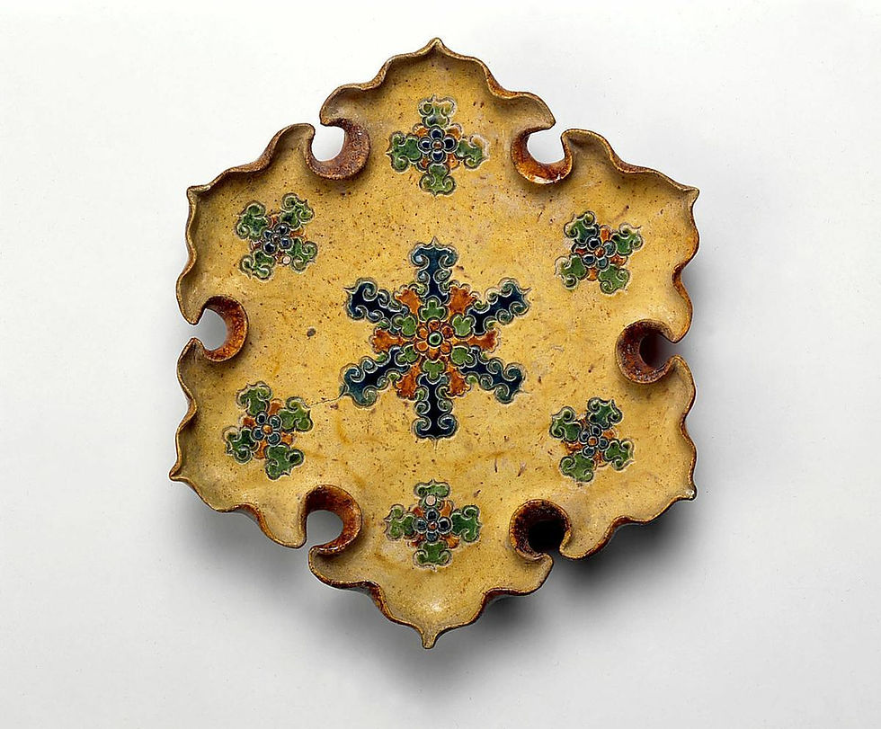 Ornate yellow ceramic dish with scalloped edges and blue-green floral motifs on a white background.