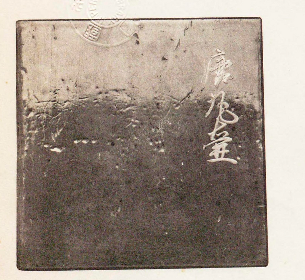 A worn metal plate with Chinese characters 唐丸壺 engraved on the right side; the surface is aged and scratched, creating an antique feel.
