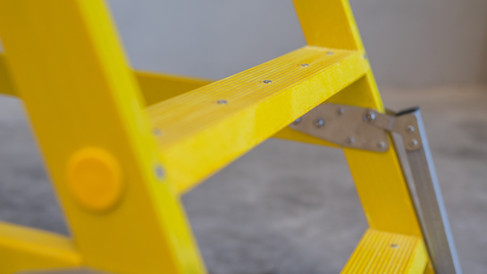 Detalle de peldaño y estructura de una escalera de fibra de vidrio amarilla para trabajos en altura