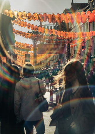 People walk in Chinatown on a sunny day, lens flares are visible. Image (c) Lenny Di Lorenzo.