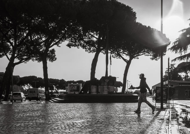 A man wearing headphones walks on the wet street pavement following a rain shower. Image (c) Lenny Di Lorenzo.