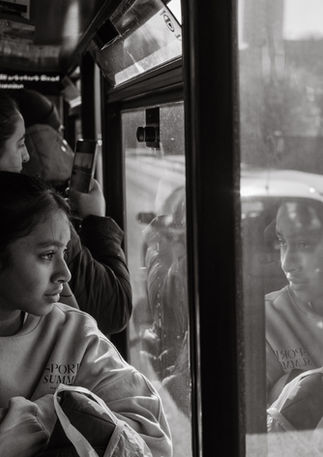 A young Indian girl looks outside a London bus, her image reflects in the window. Image (c) Lenny Di Lorenzo.