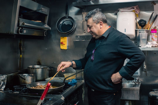 A middle age Kurdish man is cooking in his kitchen.  Image (c) Lenny Di Lorenzo.