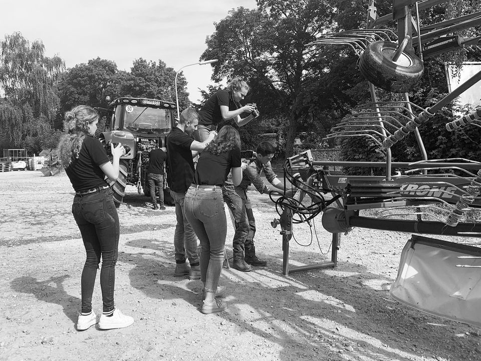 Unser Videoteam steht mit Kameras vor einem Traktor und filmt, wie an der Gelenkwelle gearbeitet wird.