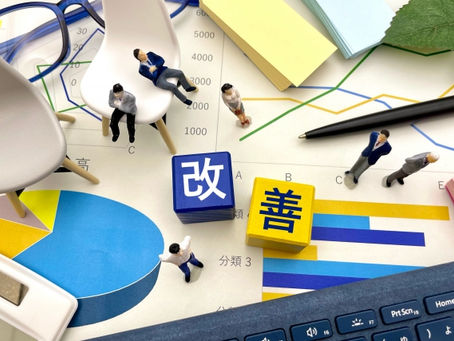 様々なグラフデータの上に、改善という文字がブロックで一文字づつ置かれている。