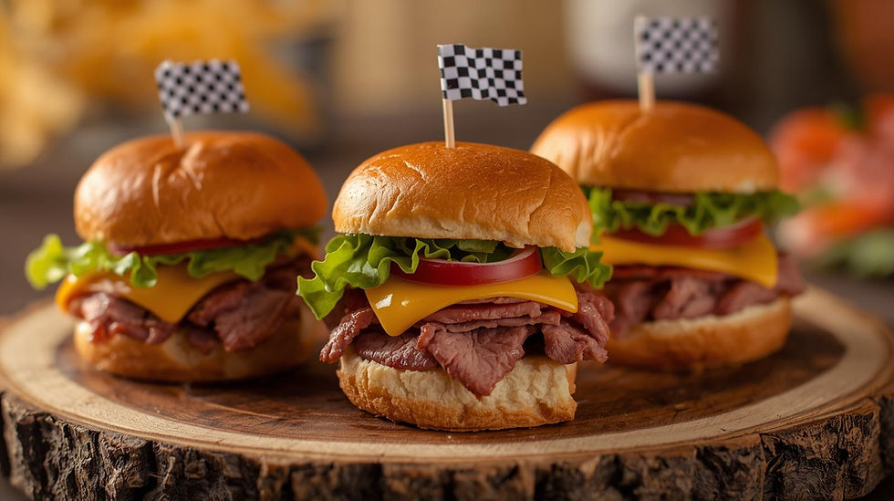 Three sliders with roast beef, cheese, lettuce, and tomato on wooden platter. Each has a black-and-white checkered flag toothpick.