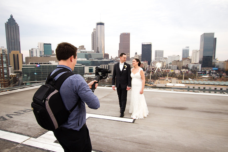 wedding videographer in Atlanta filming bride and groom on rooftop with ferris wheel in background