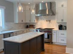 side view of kitchen remodel with grey kitchen island and white cabinets