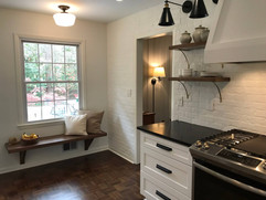 kitchen remodel with open upper shelving and built in bench under large window