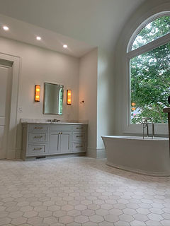 bathroom renovation with tub under window and grey cabinets